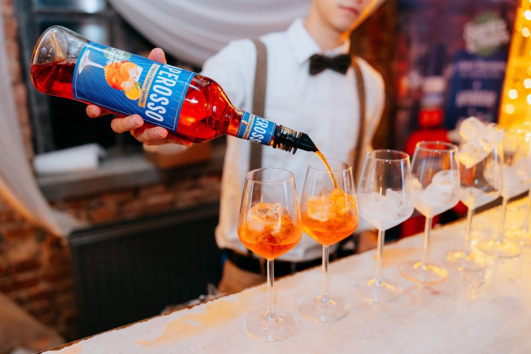 Točenje Aperosso Spritz koktela iz boce u čašu – osvježavajući talijanski aperitiv s Proseccoom i Aperitivom